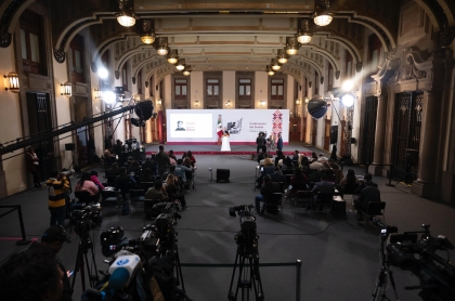 Salón de conferencias de prensa con un podio gubernamental y cámaras de medios de comunicación, sin funcionarios identificables