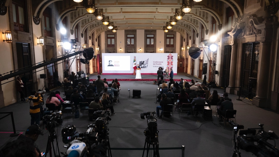 Salón de conferencias de prensa con un podio gubernamental y cámaras de medios de comunicación, sin funcionarios identificables