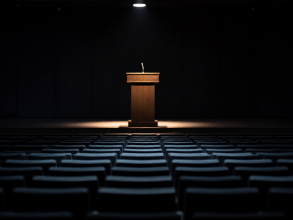 Auditorio vacío en penumbra con un atril iluminado, en referencia a las conferencias privadas de Peter Thiel sobre el Anticristo.