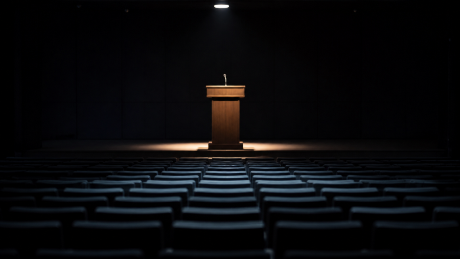 Auditorio vacío en penumbra con un atril iluminado, en referencia a las conferencias privadas de Peter Thiel sobre el Anticristo.