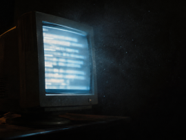 Pantalla de computadora antigua encendida en una habitación a oscuras, en referencia al origen del movimiento neorreaccionario en blogs.
