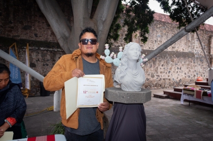 El Ganador del Premio estatal de artesanias posa junto a su obra y su reconocimiento